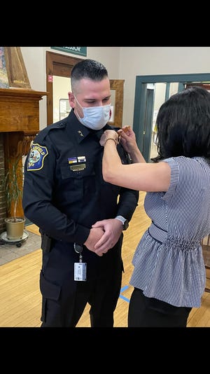 New Plainfield police Chief Mario Arriaga gets his badge pinned on by his wife, Michelle, on Monday.