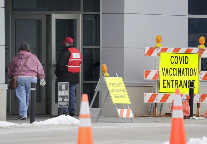A volunteer holds the door open at the COVID-19 vaccine clinic at the Fox Cities Exhibition Center in Appleton on Tuesday.