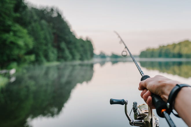 Fisherman with rod, spinning reel on the river bank.