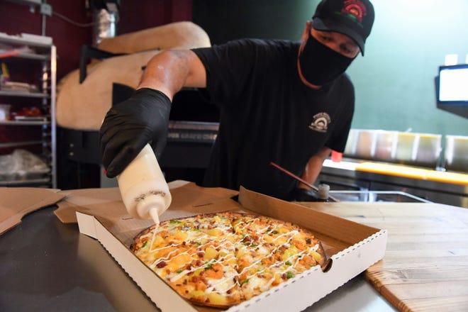 Steve Esser drizzles sauce on the Buffapeno pizza, the inspiration for the Uptowner burger, on Tuesday, Feb. 2, at Papa Woody's in Sioux Falls.
