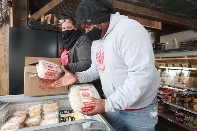 Autumn Johnson, left, and Marcus Walker, owners of The Pierogi Lady, replenish their pierogies in a freezer case at The Farmer's Rail while dropping off an order to the market and butcher shop last week in Bath.