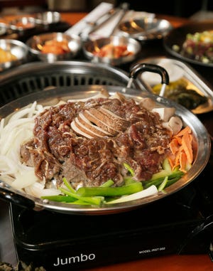 Beef Bulgogi and side vegetables is cooked at a table in the dining room of Korean BBQ restaurant Don Pocha.