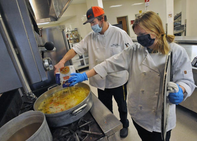 Quincy High School culinary arts instructor Mark Kelly and senior student Megan MacNeil pour chicken broth into a pan as they prepare the sauce for chicken piccata lunches that will be served at Father Bill's Place, Friday, Feb. 5, 2021.