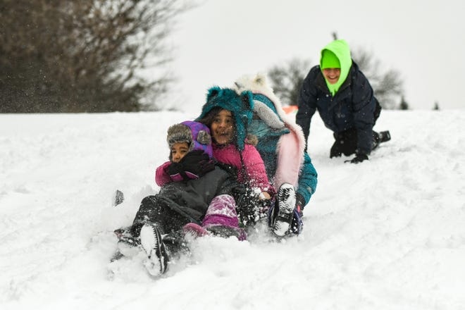 Antonio Pena, 4, cousin Lilyana Cisneros, 7, and sister Madizaya Pena, 7, of Lansing get a push from Aurerlia Cisneros while sleding on the hill at Quentin Park in Lansing, Friday, Feb. 5, 2021.