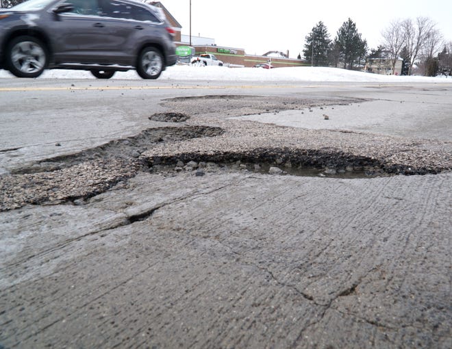    Plenty of these sharp-edged potholes await drivers along Canton Center Road near Warren.                                                         