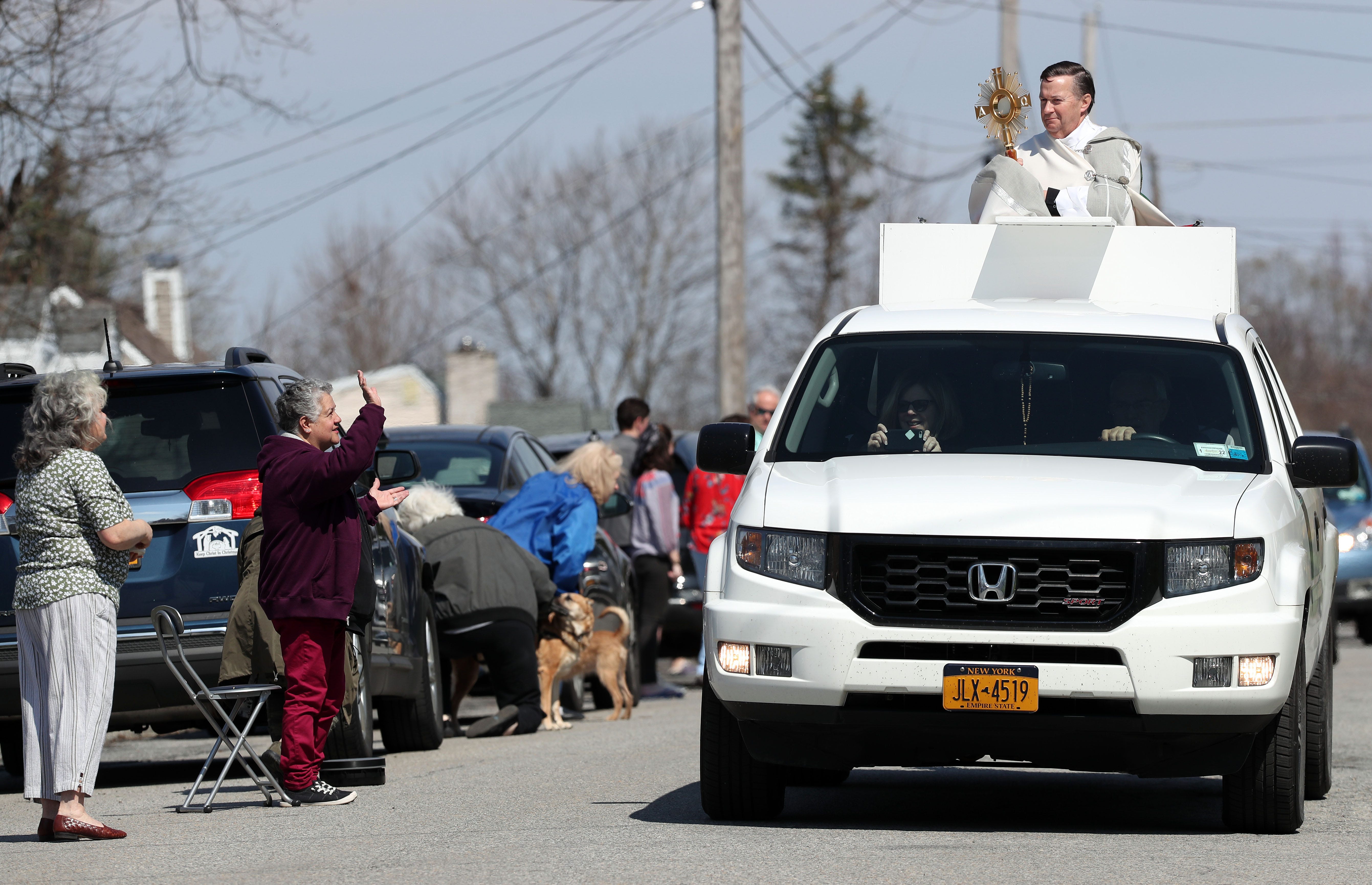 Spiritual leaders took creative measures to mark the holiest days of the year. Saint Lawrence O'Toole Church's pastor, Rev. Richard Gill, is shown here riding in the back of a big SUV in Brewster on Easter Sunday, blessing those who line the streets.