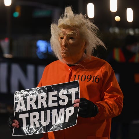 A man dressed as Trump in a prison jump suit prote