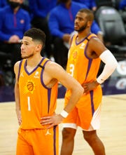 Feb. 5, 2021; Phoenix, Arizona, USA; Suns' Chris Paul (3) and Devin Booker (1) watch as the Pistons take free throws during the first half at the Phoenix Suns Arena. Mandatory Credit: Patrick Breen-Arizona Republic