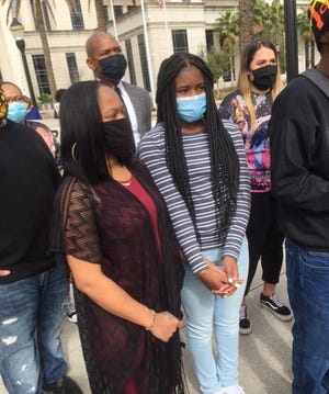 Diamonds Ford and her 12-year-old daughter listen as demonstrators demand State Attorney Melissa Nelson drop all charges against Ford in the shooting of a Jacksonville police officer in September 2020. About two dozen protesters who gathered outside the Duval County Courthouse on Monday also accused the Jacksonville Sheriff's Office of systemic racism, and demanded a ban on "no-knock" warrants.