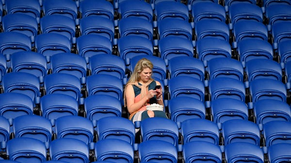 A woman looks down at her phone before the start o