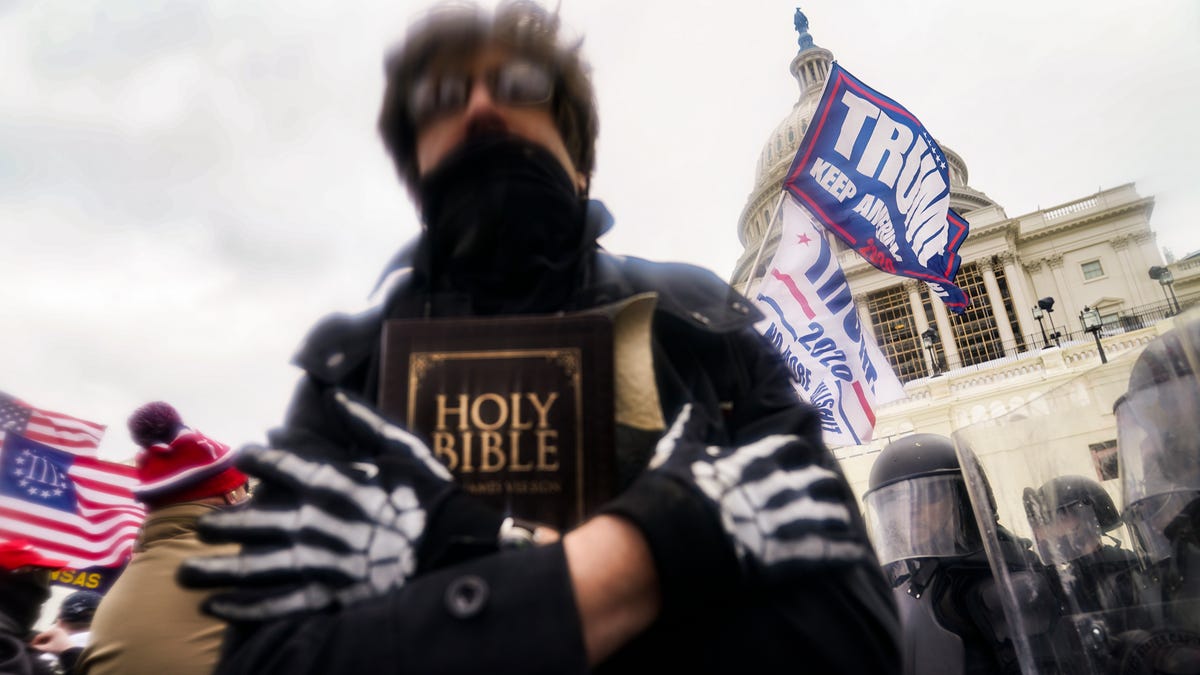 In this Wednesday, Jan. 6, 2021 file photo, a man holds a Bible as Trump supporters gather outside the Capitol in Washington. The Christian imagery and rhetoric on view during this month's Capitol insurrection are sparking renewed debate about the societal effects of melding Christian faith with an exclusionary breed of nationalism.