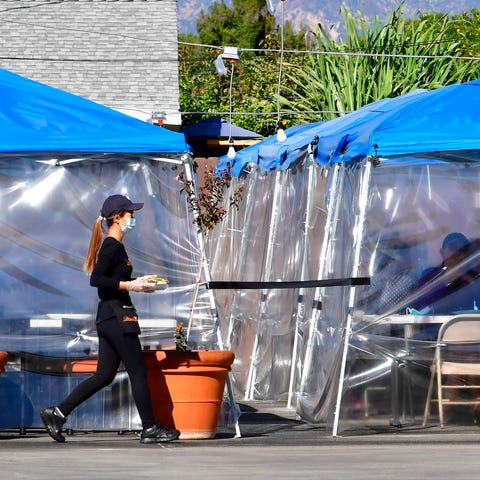 A waitress delivers orders to diners seated outdoo