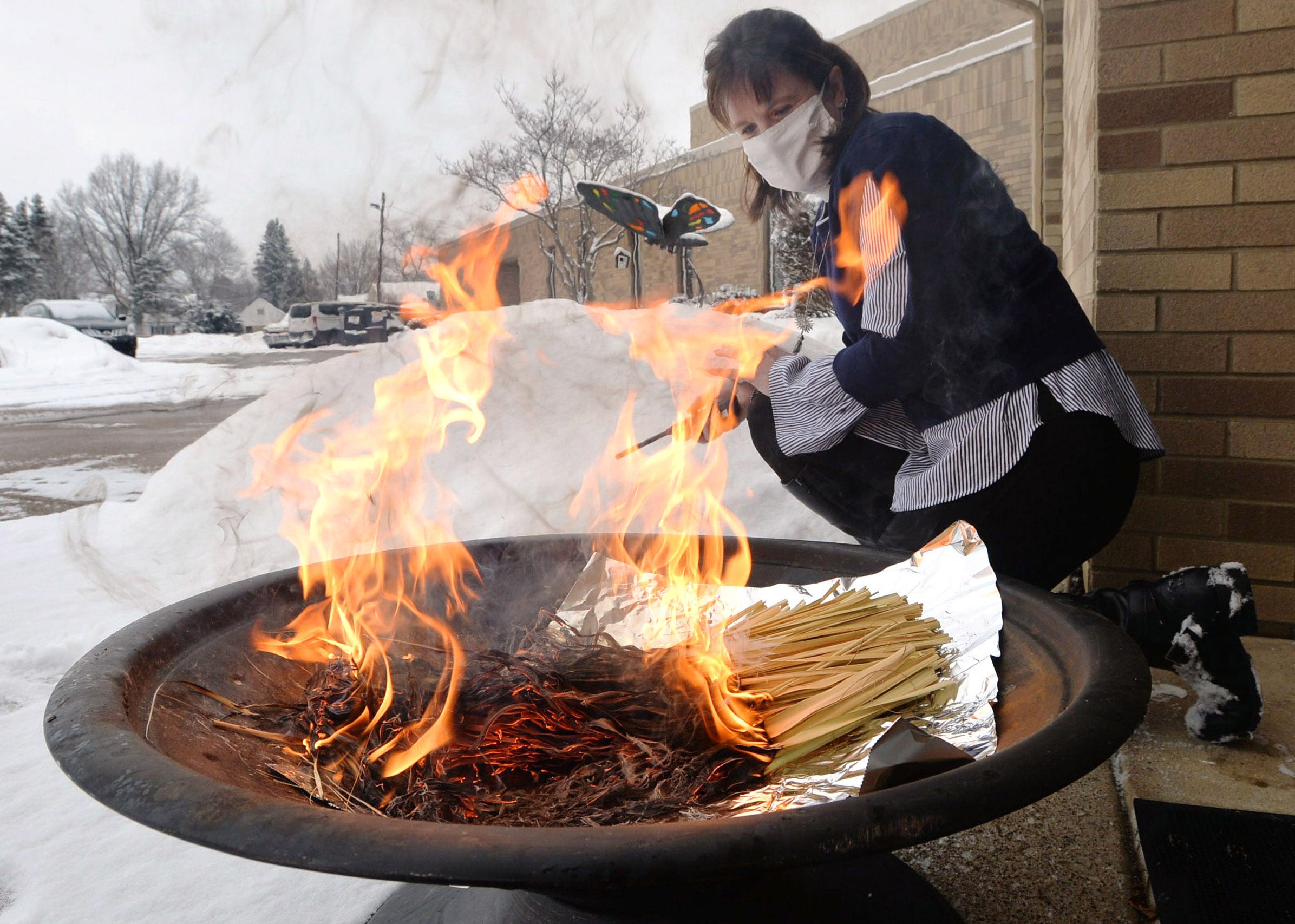 The Rev. Sami Pfalzgraf burns palm fronds to create the ashes to be used in Ash Wednesday services at St. Paul's Lutheran Church on Feb. 9, 2021, in Millcreek Township. Due to the COVID-19 pandemic, she is bagging up small amounts of ash and handing them out so people can observe Ash Wednesday safely in small groups.