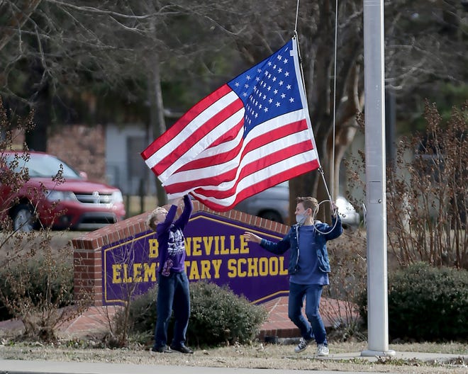 Two boys lower the American flag at the end of the school day, Wednesday, Jan. 13, at the Booneville Elementary School.