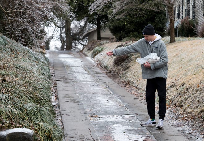 Payton Peckenpaugh throws salt over his driveway off North Main Street in Downtown Henderson, Ky., Thursday afternoon, Feb. 11, 2021. A second wave of winter weather hit the area Wednesday evening, creating a sheet of ice that caused damage and hazardous road conditions throughout the Tri-State.