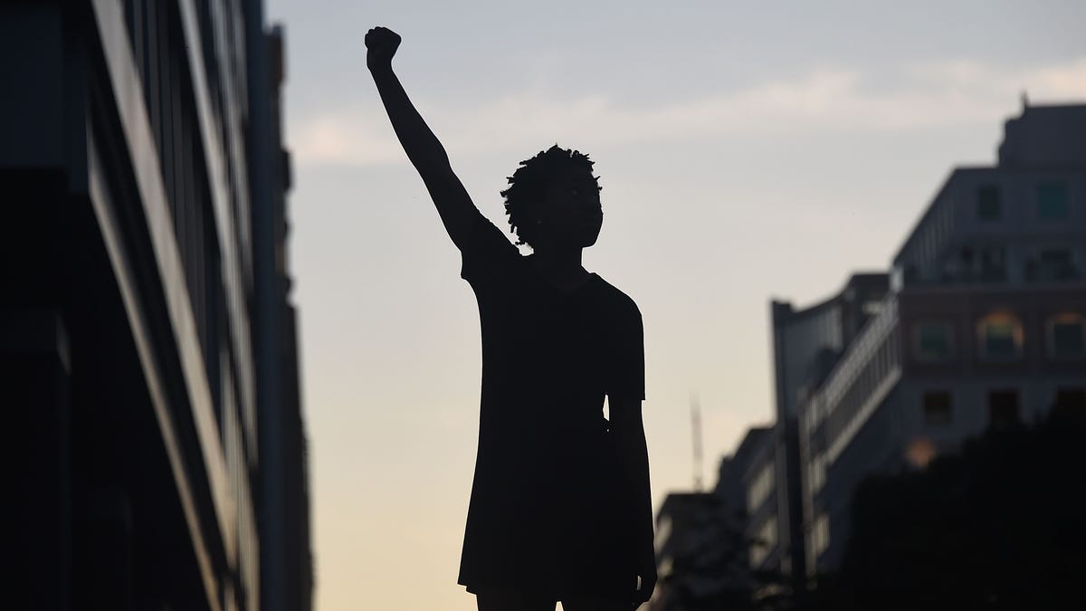 A demonstrator's silhouette is seen as they raise a fist during a protest against police brutality and the death of George Floyd, near the White House on June 7, 2020 in Washington, DC.
