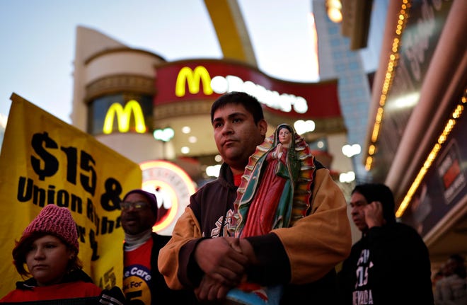 Martin Macias-Rivera holds a statue as he and others protest near a McDonald's restaurant along the Las Vegas Strip, Tuesday, Nov. 29, 2016, in Las Vegas. The protest was part of the National Day of Action to Fight for $15. The campaign seeks higher hourly wages, including for workers at fast-food restaurants and airports.