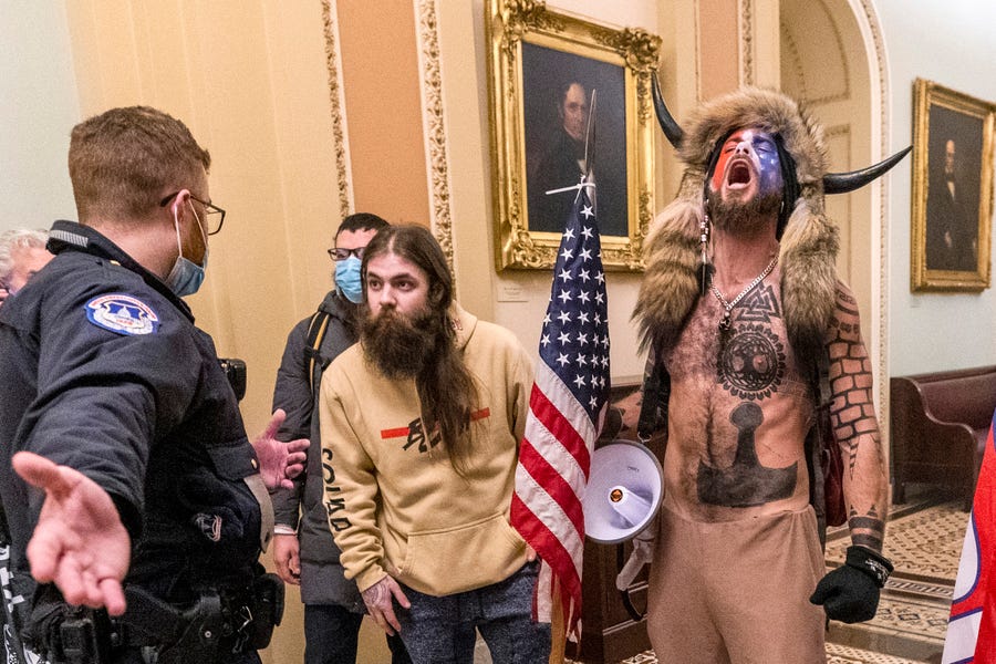 Supporters of President Donald Trump, including Jacob Chansley, right with fur hat, are confronted by U.S. Capitol Police officers outside the Senate Chamber inside the Capitol in Washington on Jan. 6, 2021.