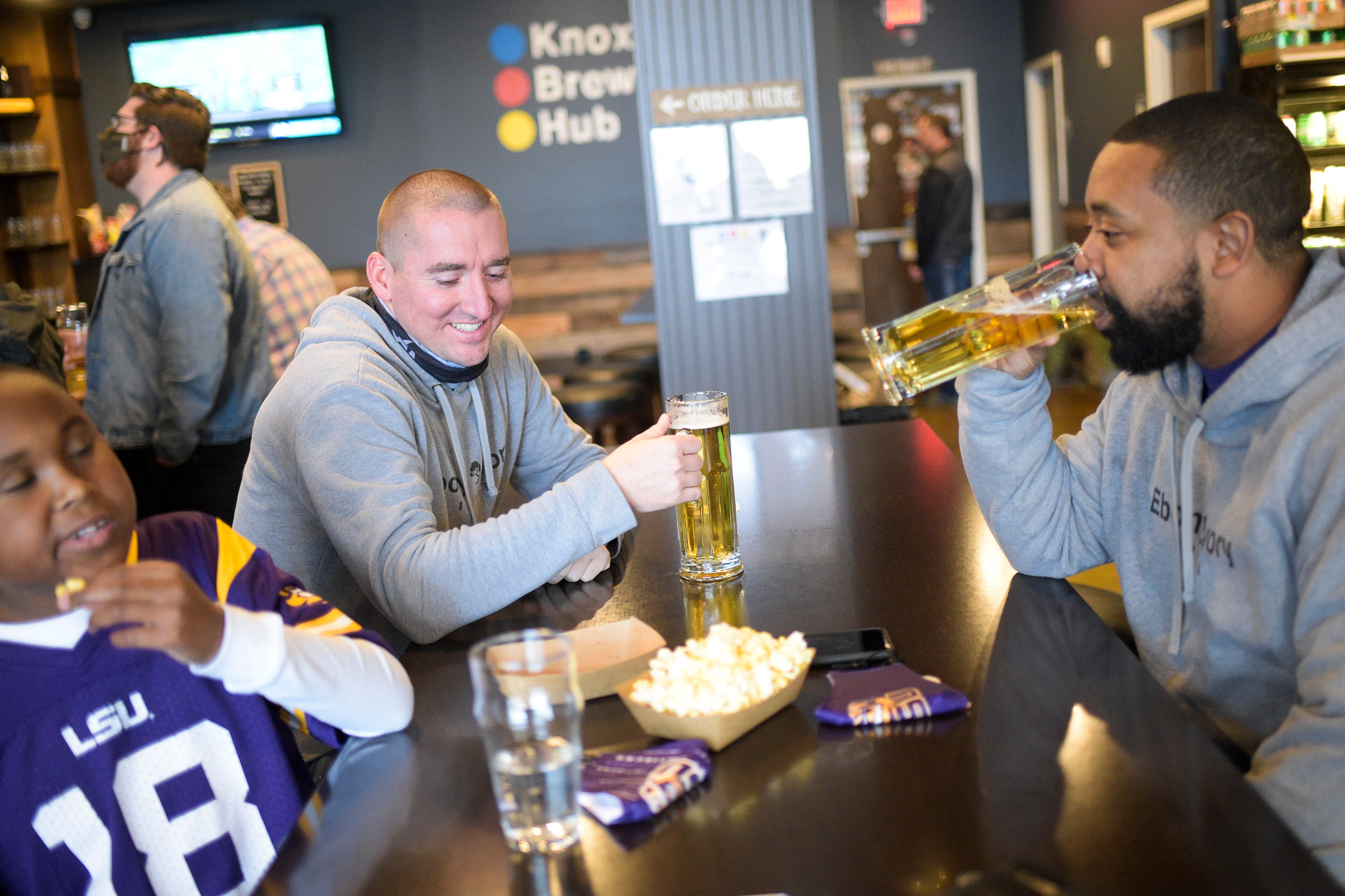 From left, Quincy Dupas, Mitchell Russell and Chico Dupas drink beer and eat popcorn at Knox Brew Hub in downtown Knoxville, Tenn. on Saturday, Feb. 13, 2021.