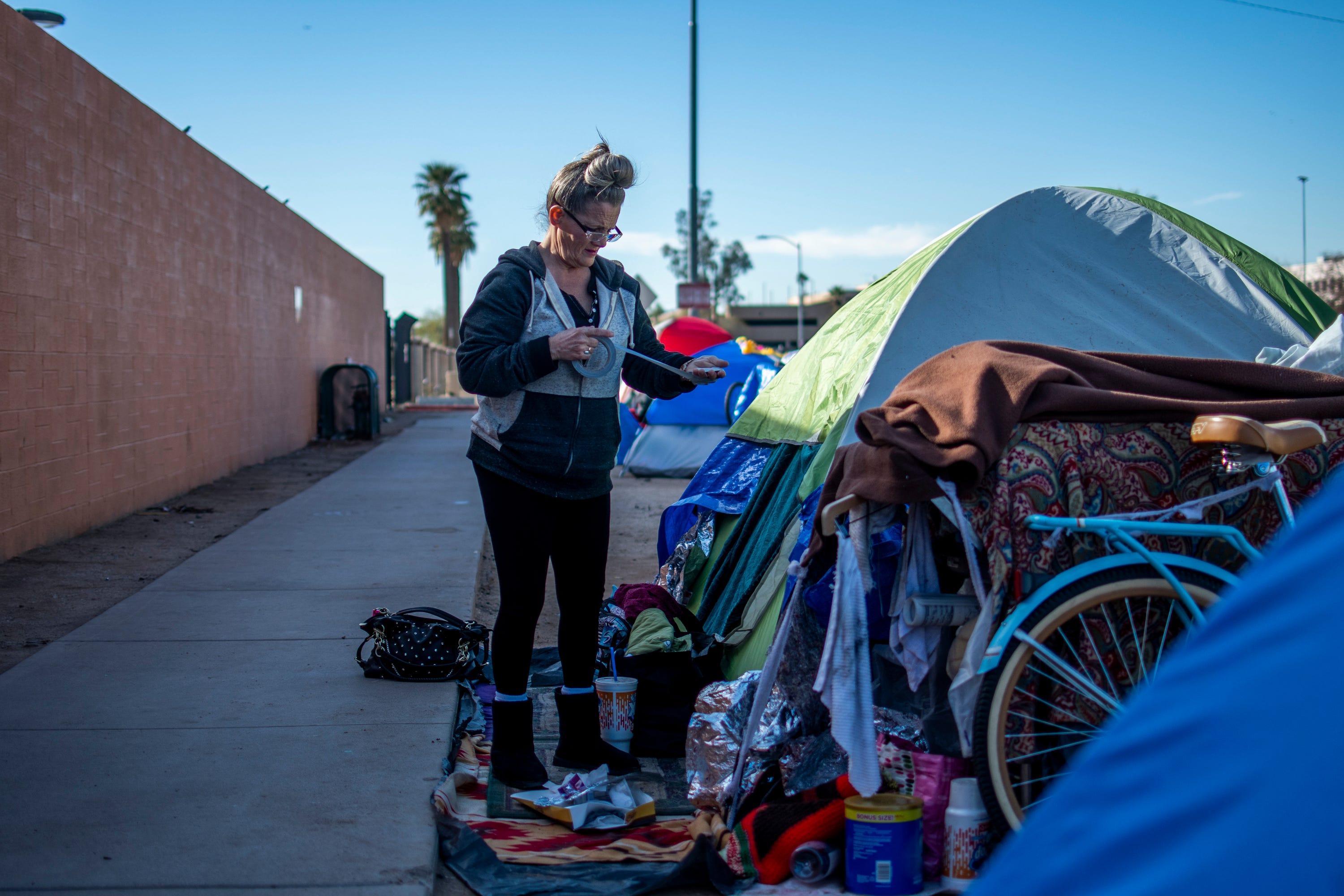 Darlene Carchedi makes a lint roller out of duct tape outside her tent in downtown Phoenix on Jan. 3, 2020. She says that when officials clean up homeless encampments, the trauma of being homeless repeats itself.