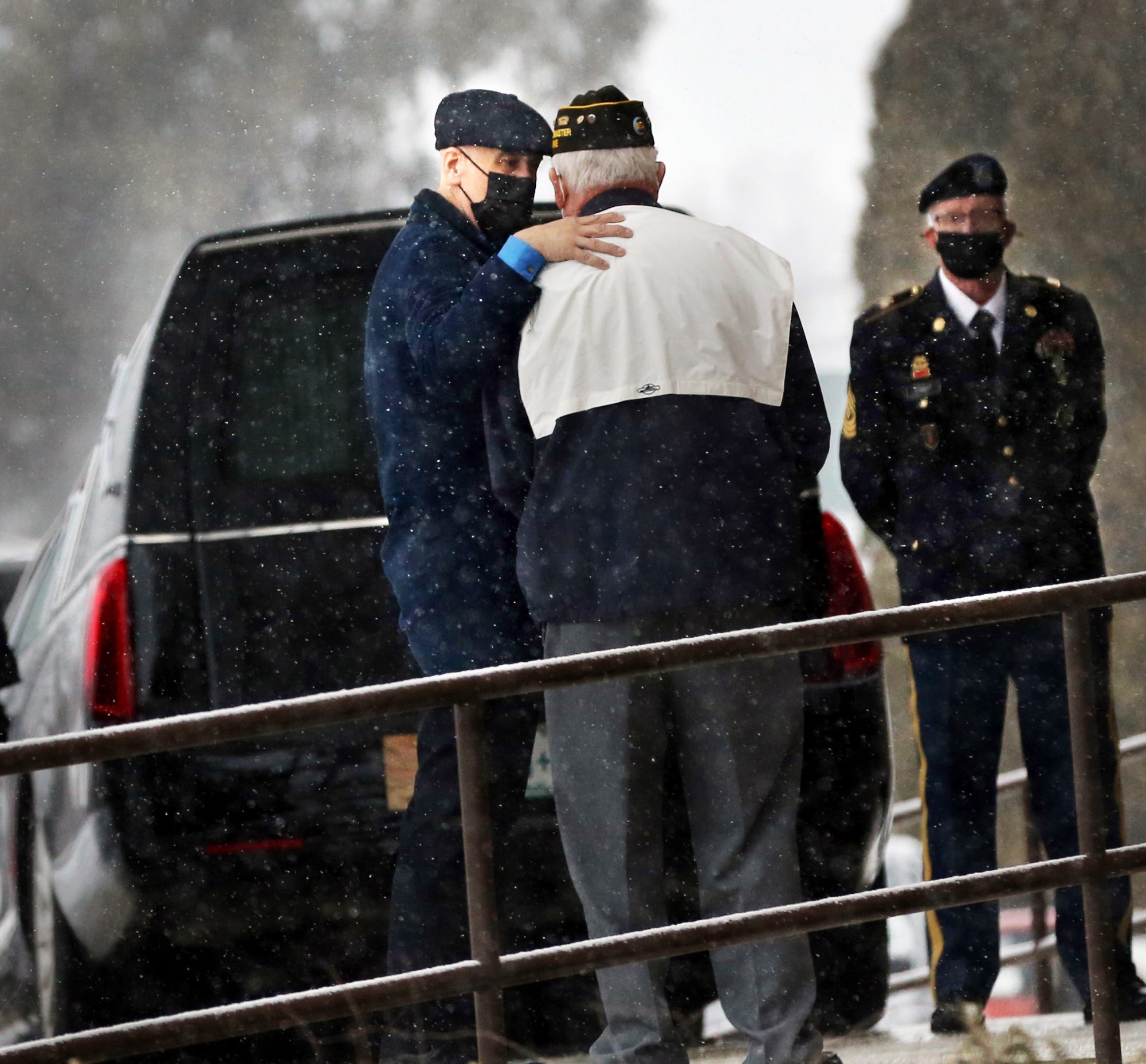 As snow falls gently, funeral home director Jeff Pelkey comforts a friend of the deceased during a funeral Mass. The gentleman, who was cremated, was a Korean War veteran who was heavily involved with the VFW.