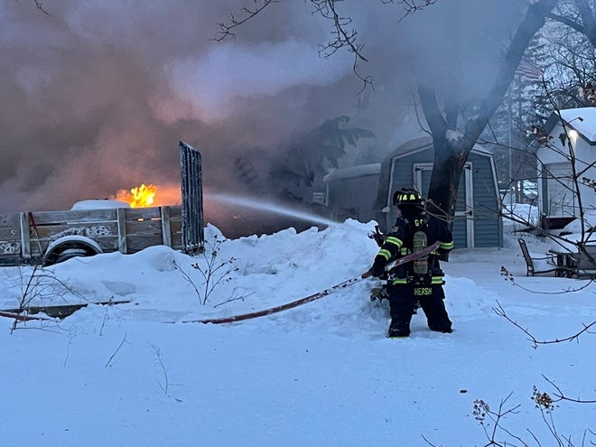 Germantown firefighters stand in knee-deep snow as they fight a garage fire in the W15900 block of Main Street in the village just before 5 p.m. Monday.