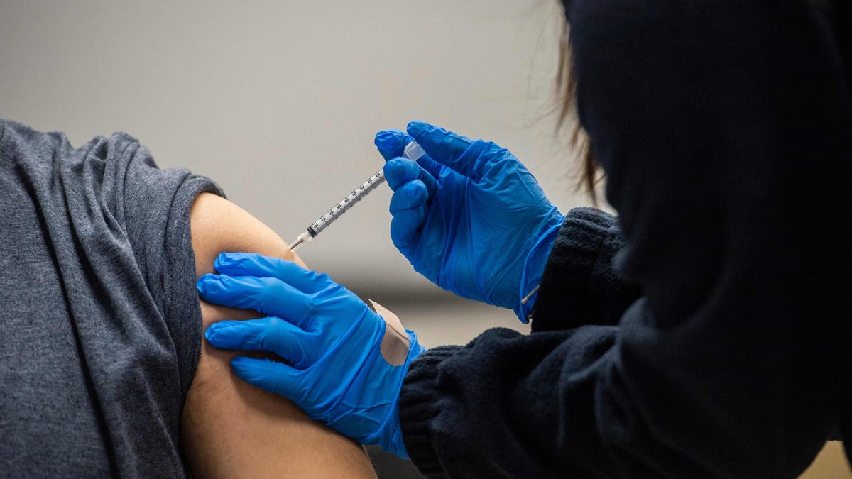 A man is inoculated with the Pfizer-BioNTech Covid-19 vaccine at La Colaborativa in Chelsea, Massachusetts on February 16, 2021. - Chelsea, with a population of close to 40,000 people, is one of the hardest hit cities in the United States by Covid-19 with close to 8,000 infected people and over 200 deaths from the virus.  The community is made up of close to 70 percent Latino or Hispanic people and also retains a large undocumented population.  East Boston   Neighborhood Health Center is working with La Colaborativa to vaccinate any person in the community that wants to be vaccinated and is working to get the message out in multiple languages.  Signs are outside the building in Spanish and English.  La Colaborativa is all ready an established institution in the community for helping and empowering immigrants in the city. (Photo by Joseph Prezioso / AFP) (Photo by JOSEPH PREZIOSO/AFP via Getty Images) ORG XMIT: 0 ORIG FILE ID: AFP_9368HE.jpg