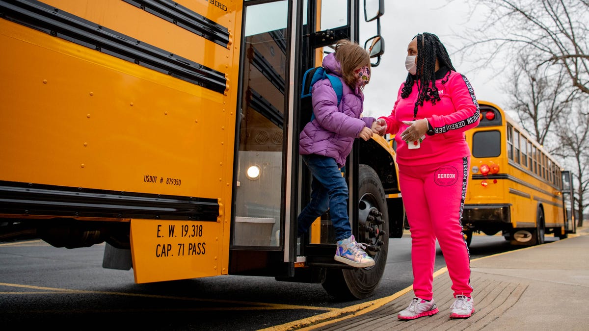 Olivia Jones-Martin, a pre-kindergarten instructional aid, helps students get off the bus on Feb. 1, 2021, at Parrish Elementary School in Carbondale, Ill. The school is taking various precautions, such as limited classroom sizes and social distancing, to prevent the spread of the novel coronavirus. 