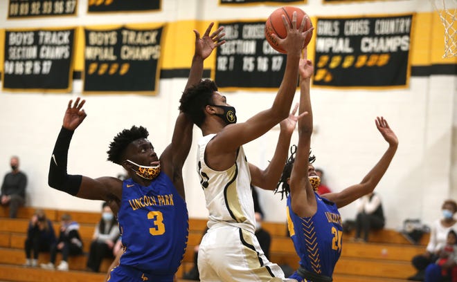 Quaker Valley's Markus Frank (13) attempts a layup while being heavily guarded by Lincoln Park's Dakari Bradford (3) and Brandin Cummings (24) during the first half Tuesday night at Quaker Valley High School.