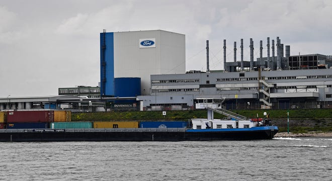 In this May 4, 2020, file photo, a container ship passes the Ford car plant in Cologne, Germany, as the US car maker restarts the production after the coronavirus lockdown. Ford says it will spend $1 billion to modernize its Cologne, Germany, manufacturing center, converting it into a European electric vehicle factory.