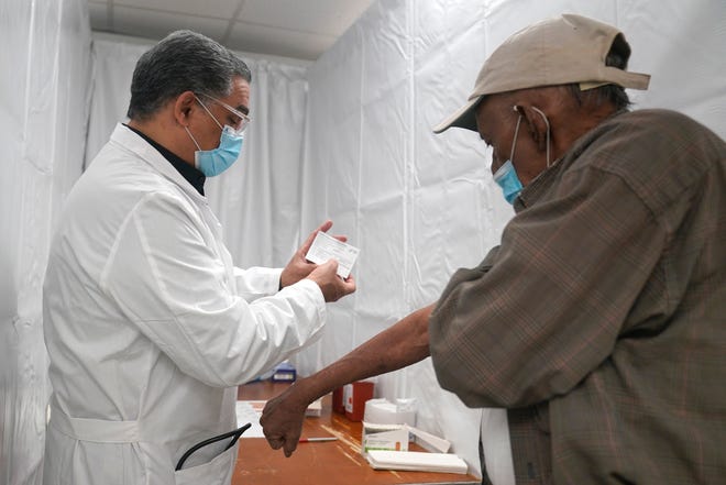 Dr. Victor Peralta, left, examines Sundar Surujmohan's vaccination card before giving him his second dose of COVID-19 vaccine in New York City on Feb. 5.