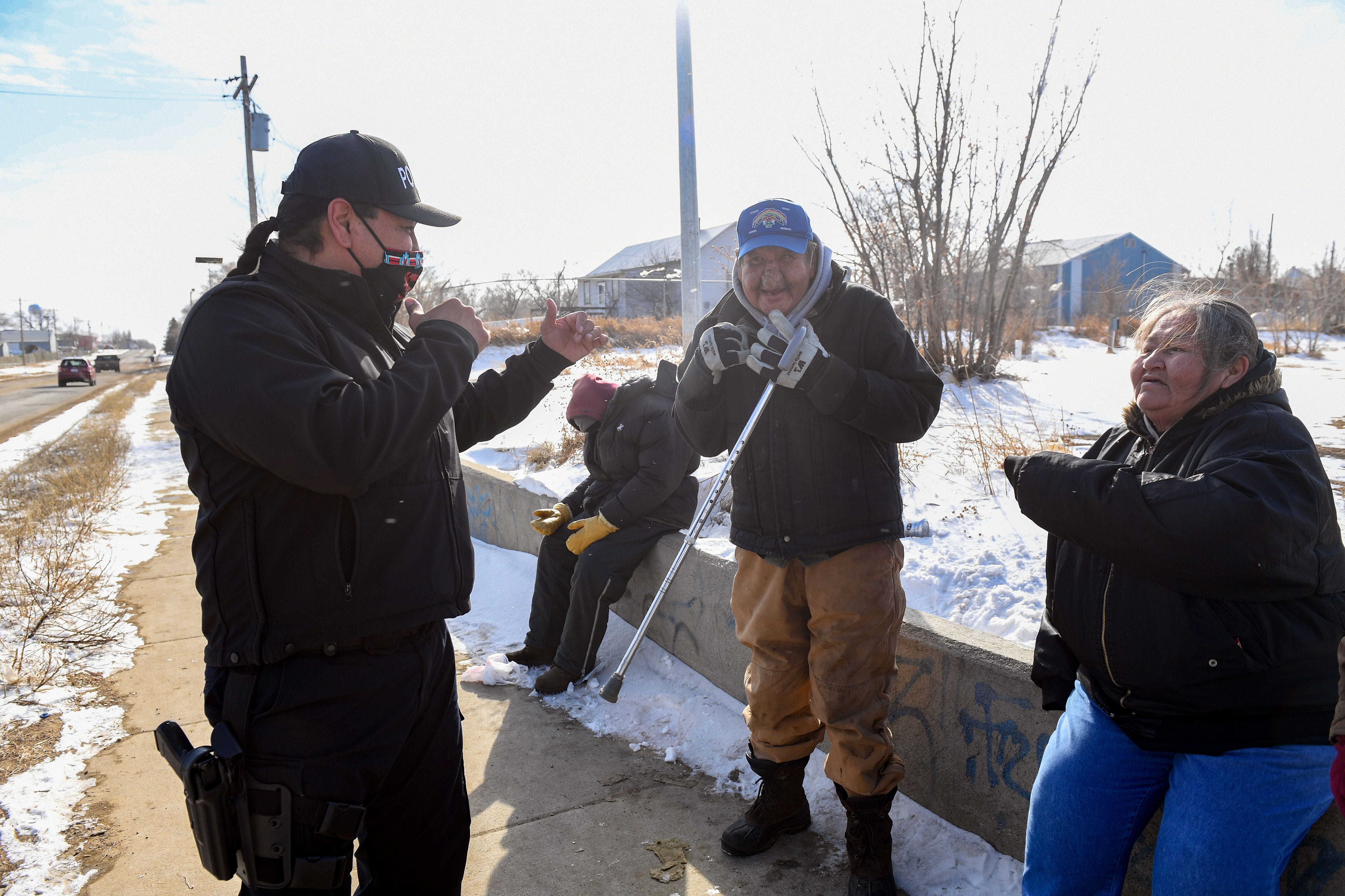 Joe Brings Plenty jokes with tribal members Delwayne "Pancho" Larrabee and Tammy Crow while on duty Feb. 17 in Eagle Butte, South Dakota. The couple live on the streets.