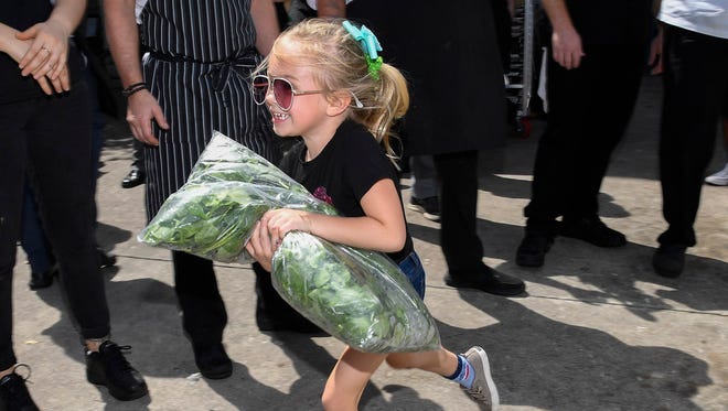 Skylar Horschel, the daughter of PGA Tour player Billy Horschel, helps load a bag of lettuce on a truck bound for the Feeding Northeast Florida warehouse on Industrial Boulevard in Jacksonville.
