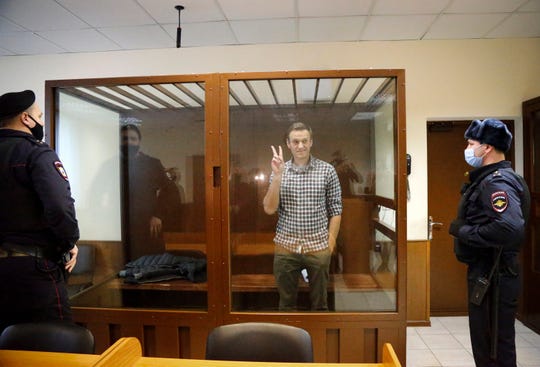Opposition leader Alexei Navalny stands in a cage in the Babuskinsky District Court in Moscow, Russia, Saturday, Feb. 20, 2021. Two trials against Navalny are being held Moscow City Court one considering an appeal against his imprisonment in the embezzlement case and another announcing a verdict in the defamation case.