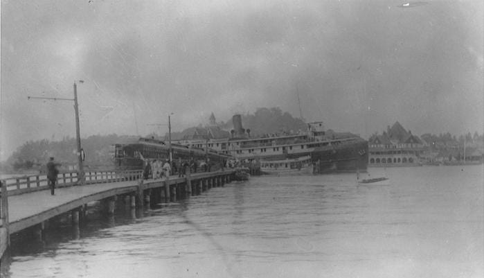 A large steamboat from Chicago docks at Macatawa Park in Holland. Many passengers from these boats were transported to the Hotel Ottawa by railway. In the background, the relocated and renovated Ottawa Beach Hotel is visible.