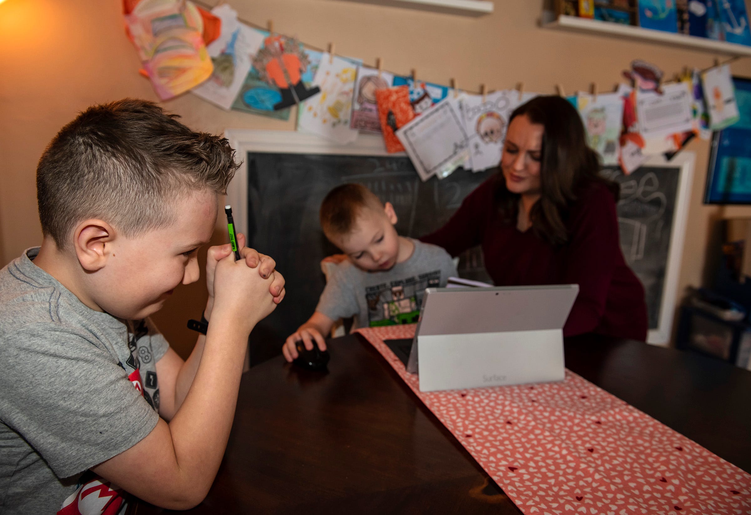 Cameron Baughman, 8, left, thinks hard about a multiplication problem given him by his mom, Jamie Baughman, who is also helping her younger son Gage, 6, do his homework in their Rochester Township home.