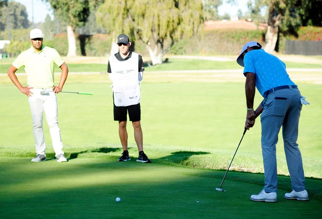 Max Homa putts on the 14th green as Tony Finau, who would later face Homa in a playoff, and caddie Mark Urbanek watch during the final round of The Genesis Invitational golf tournament Sunday at Riviera Country Club in Pacific Palisades, Calif.