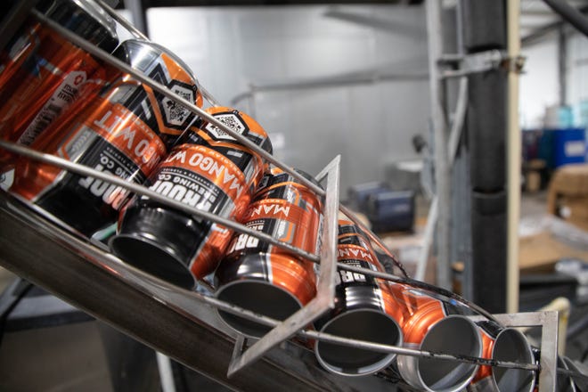 Cans of Proof Brewing Company's Mango Wit are filled at the brewery Monday, Feb. 22, 2021.