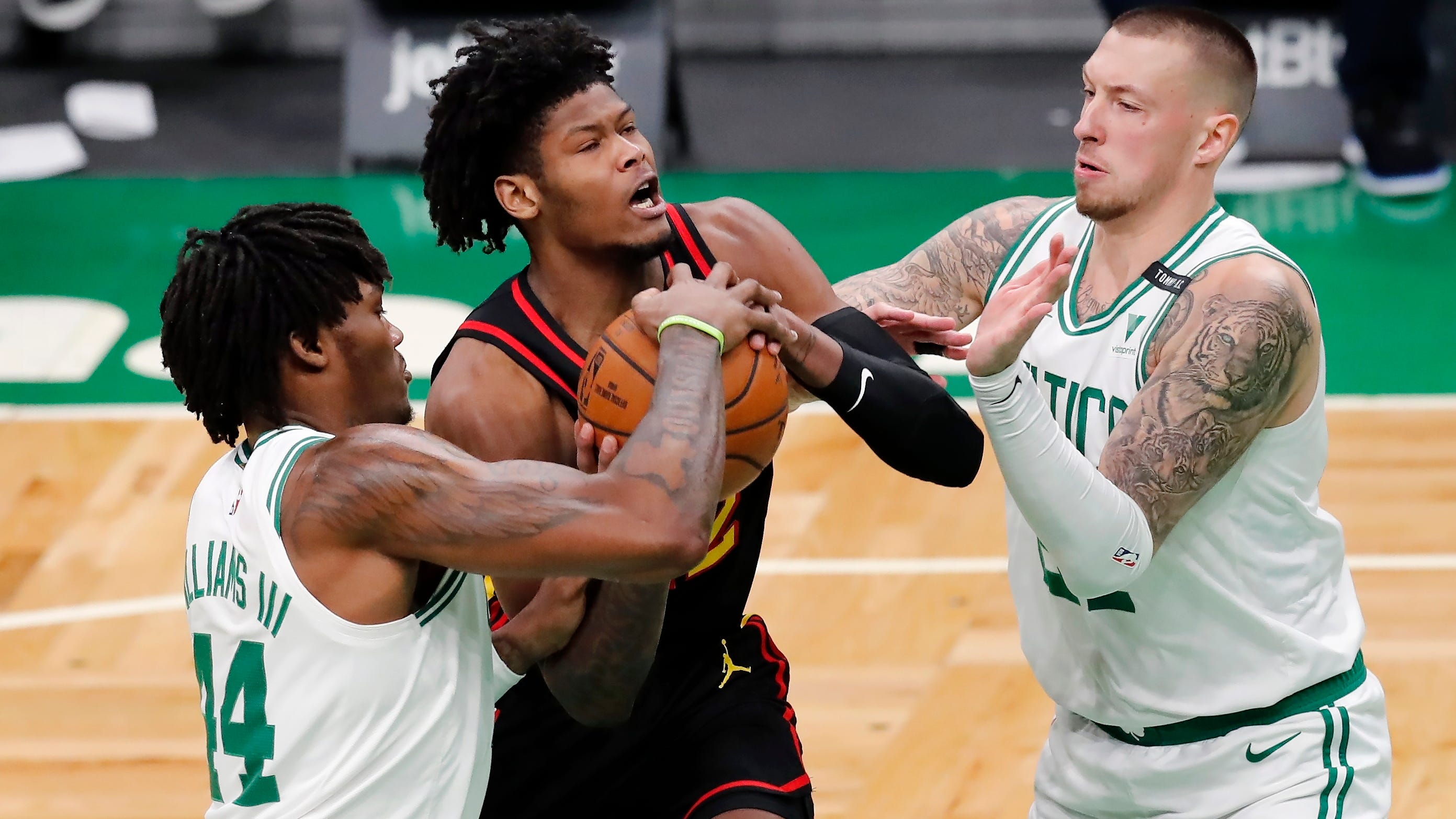 Boston Celtics' Robert Williams III (44) and Daniel Theis, right, block a drive for the basket by Atlanta Hawks' Cam Reddish in Boston.