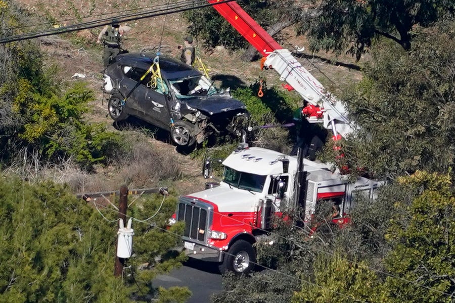 Workers move a vehicle after a rollover accident involving golfer Tiger Woods Tuesday, Feb. 23, 2021, in the Rancho Palos Verdes section of Los Angeles. 