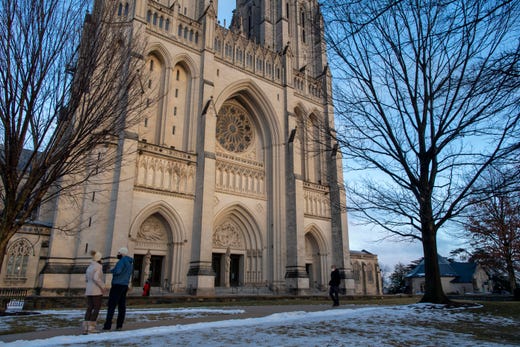 Paul Kerins and Daniela Facchini of Washington D.C. listen as the National Cathedral in Washington, D.C. rings its bells 500 times to mark 500,000 COVID-19 deaths in the U.S. on Monday, Feb. 22, 2021.