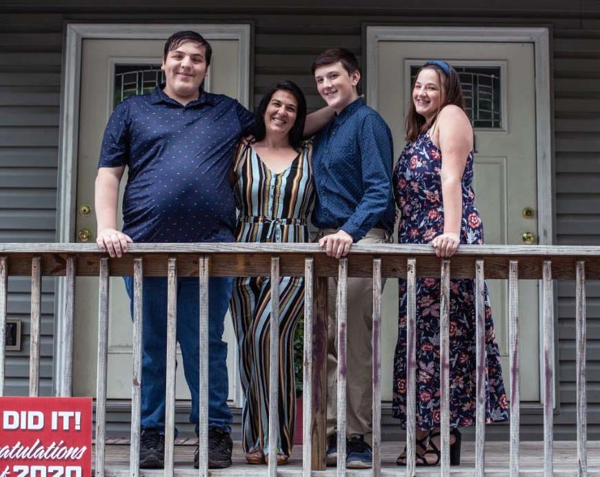 Misty Mcdade and her three children pose for a photo outside their home to celebrate her son's school graduation in Morgantown, W. Va. The single mom of three had to move from their townhouse out to a trailer after being laid off from her accounting job as a result of COVID-19.