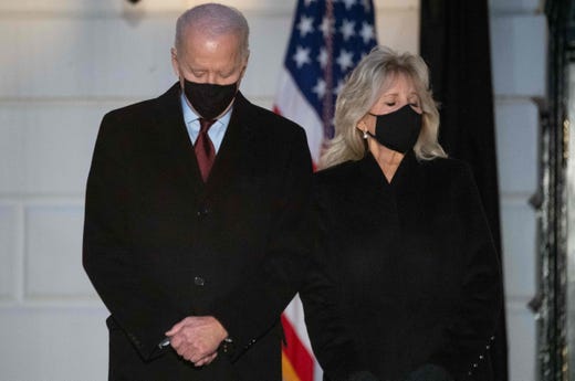 President Joe Biden and First Lady Jill Biden hold a moment of silence during a candlelight ceremony in honor of those who lost their lives to Coronavirus on the South Lawn of the White House in Washington, DC, February 22, 2021.  President Joe Biden called the milestone of more than 500,000 US deaths from COVID-19 "heartbreaking" on Monday and urged the country to unite against the pandemic. "I know what it's like," an emotional Biden said in a national television address, referring to his own long history of family tragedies.