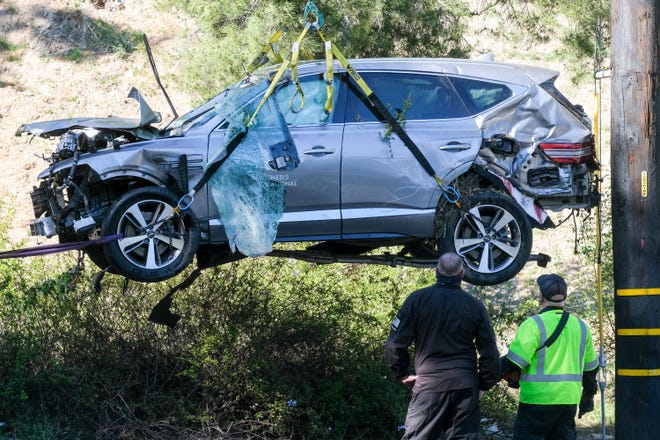 A crane is used to lift a vehicle following a rollover accident involving golfer Tiger Woods, Tuesday, Feb. 23, 2021, in the Rancho Palos Verdes suburb of Los Angeles. Woods suffered leg injuries in the one-car accident and was undergoing surgery, authorities and his manager said. (AP Photo/Ringo H.W. Chiu)