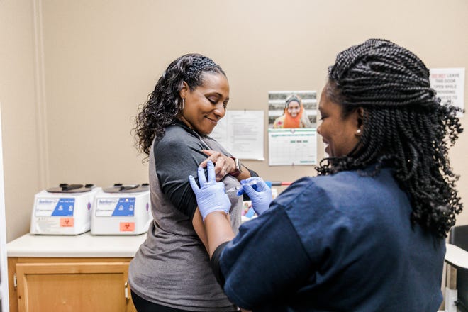 Healthcare worker Trakina Kipkemboi at the Clarksville-Montgomery County Onsite Employee Health and Wellness Clinic demonstrates how to administer a vaccine to clinic manager Sharla Smith.