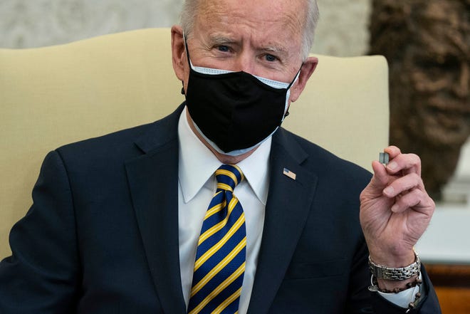 President Joe Biden holds up a microchip during a meeting with lawmakers to discuss U.S. supply chains, in the Oval Office of the White House on Feb. 24, 2021, in Washington.