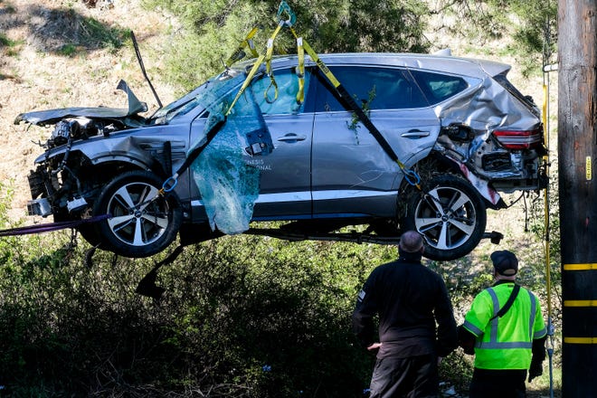 Workers watch as a crane is used to lift a vehicle following a rollover accident involving golfer Tiger Woods, Tuesday, Feb. 23, 2021, in the Rancho Palos Verdes section of Los Angeles.