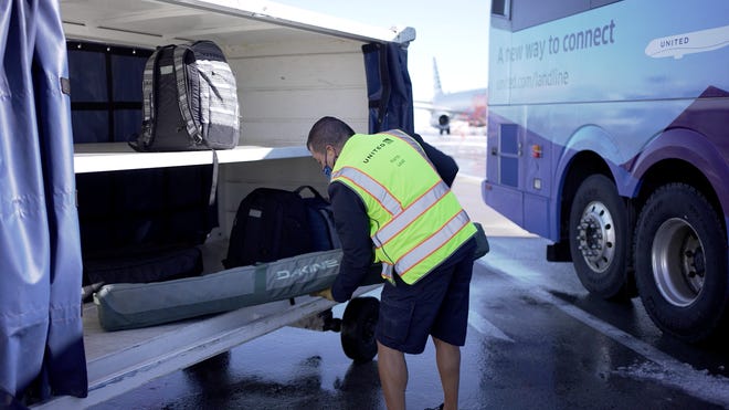 A United Airlines employee loads bags from a Landline bus that will be transferred to a United flight.
