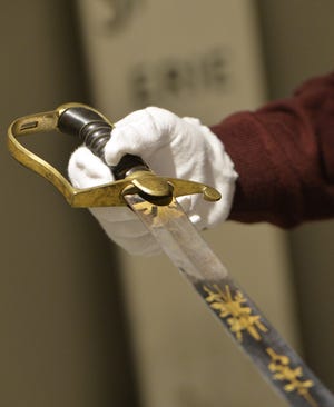 In February, Hagen History Center Museum Educator Jeff Sherry holds a sword once owned by Commodore Oliver Hazard Perry. The sword will be on display when the center reopens to the public on Saturday.