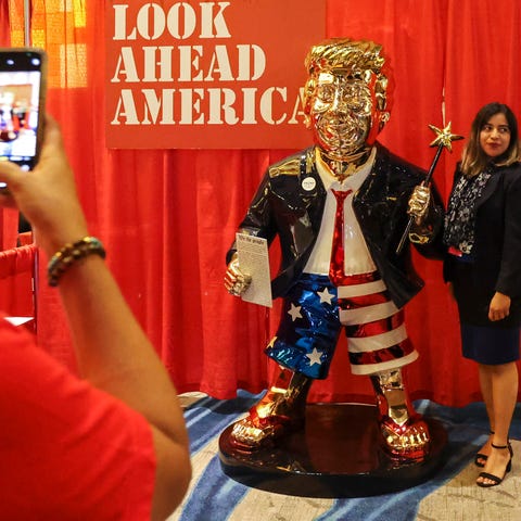 A woman takes a photo with a golden Donald Trump s